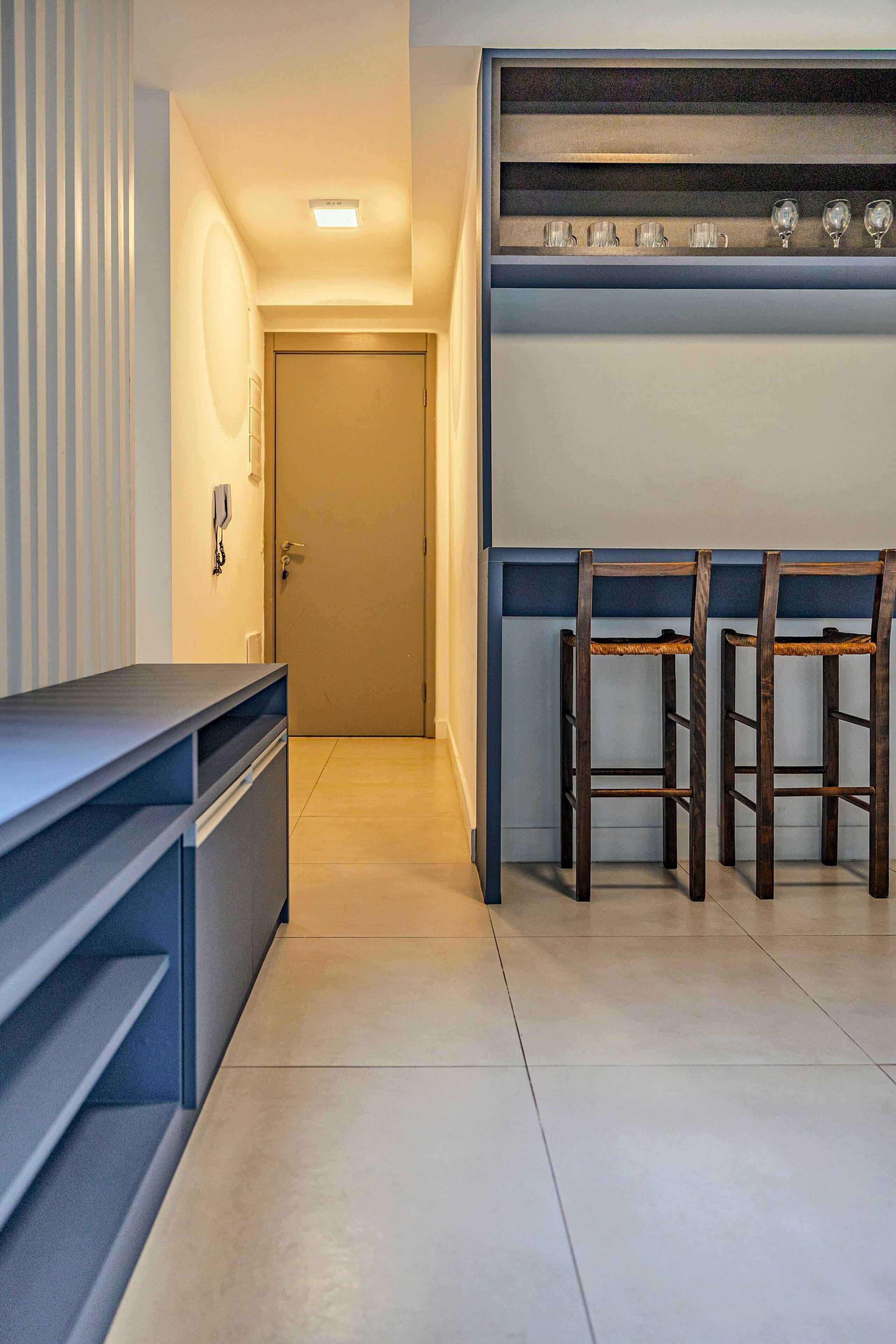 A modern kitchen with a built-in bar area, two wooden stools, and a countertop with storage drawers.