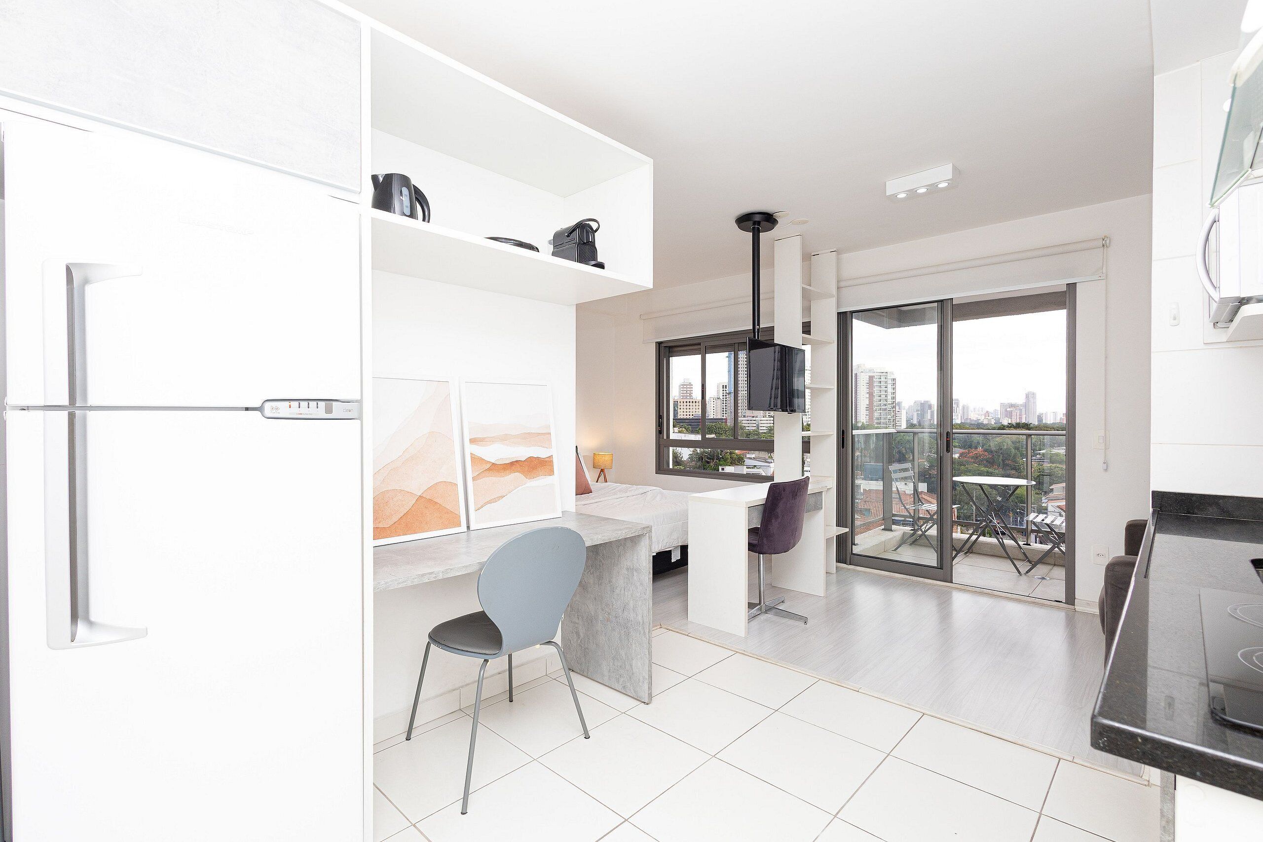 A modern kitchen with white cabinetry, a grey chair, and a dining area with a table and chairs.