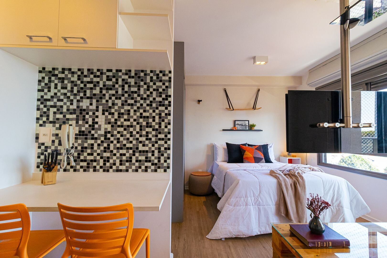 A modern bedroom with a large bed, bedside table, and a TV mounted on the wall.