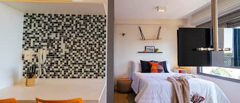 A modern bedroom with a large bed, bedside table, and a TV mounted on the wall.