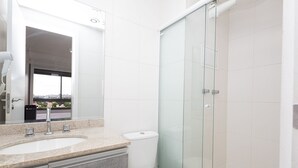 A modern bathroom with a glass shower enclosure, a sink with a marble countertop, and a toilet. - Vossa Bossa Vila Madalena Diseño (São Paulo)