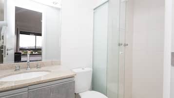 Une salle de bain moderne avec une douche à parois de verre, un lavabo doté d’un plan de toilette en marbre et des toilettes.