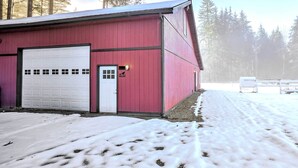 Punainen lato, jossa on valkoinen autotallin ovi, ja sen ympärillä on lumipeitteistä maastoa ja puita.