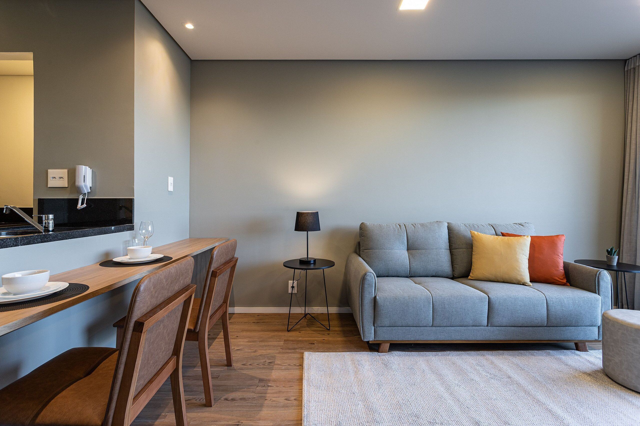 Ein modernes Wohnzimmer mit grauem Sofa, Holzes Esstisch und Stühlen.