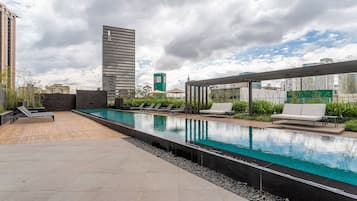 Uma área de piscina no terraço com espreguiçadeiras e um pergolado.
