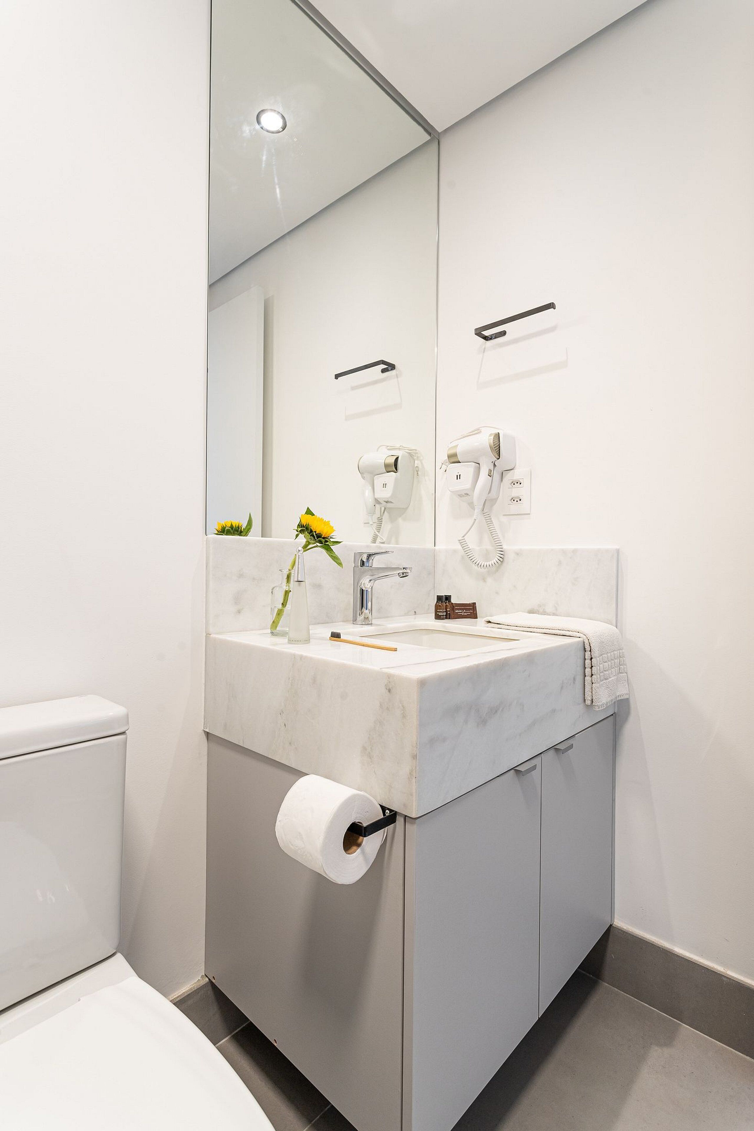 Une salle de bain moderne avec un lavabo en marbre, des toilettes et un miroir.
