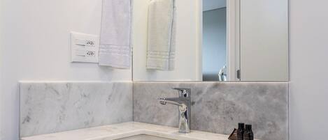 A bathroom with a marble sink, a mirror, two towels, and toiletries.
