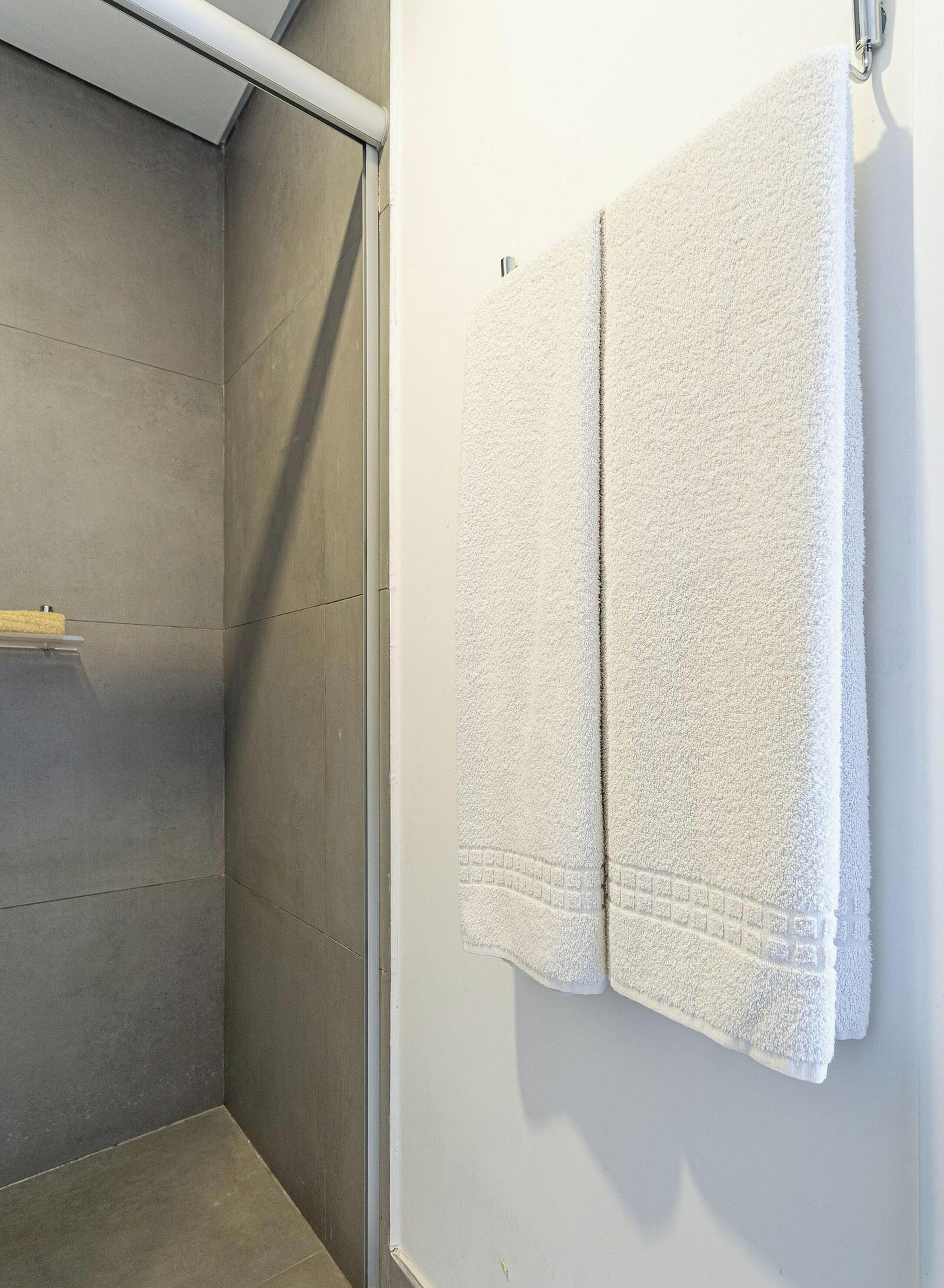 Casa de banho com área de duche e duas toalhas penduradas na parede.