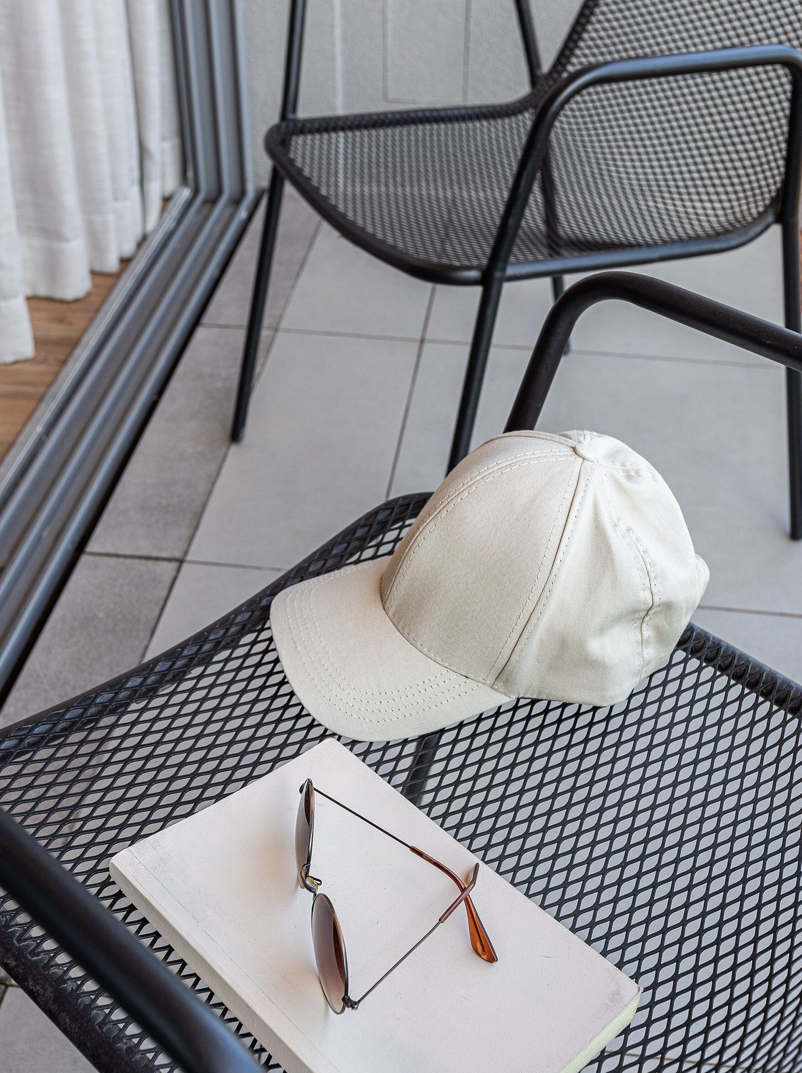 A metal table with a white cap and sunglasses on it.