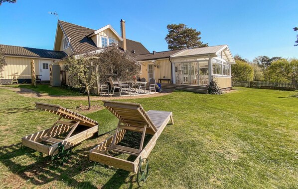 A large house with a spacious backyard, a covered patio, and a lawn with two wooden lounge chairs. - Pet friendly home in Skummeslövsstrand (Skummeslövsstrand)