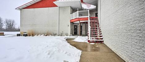 A building with a red roof and white walls, a concrete pathway, and a snow-covered ground.