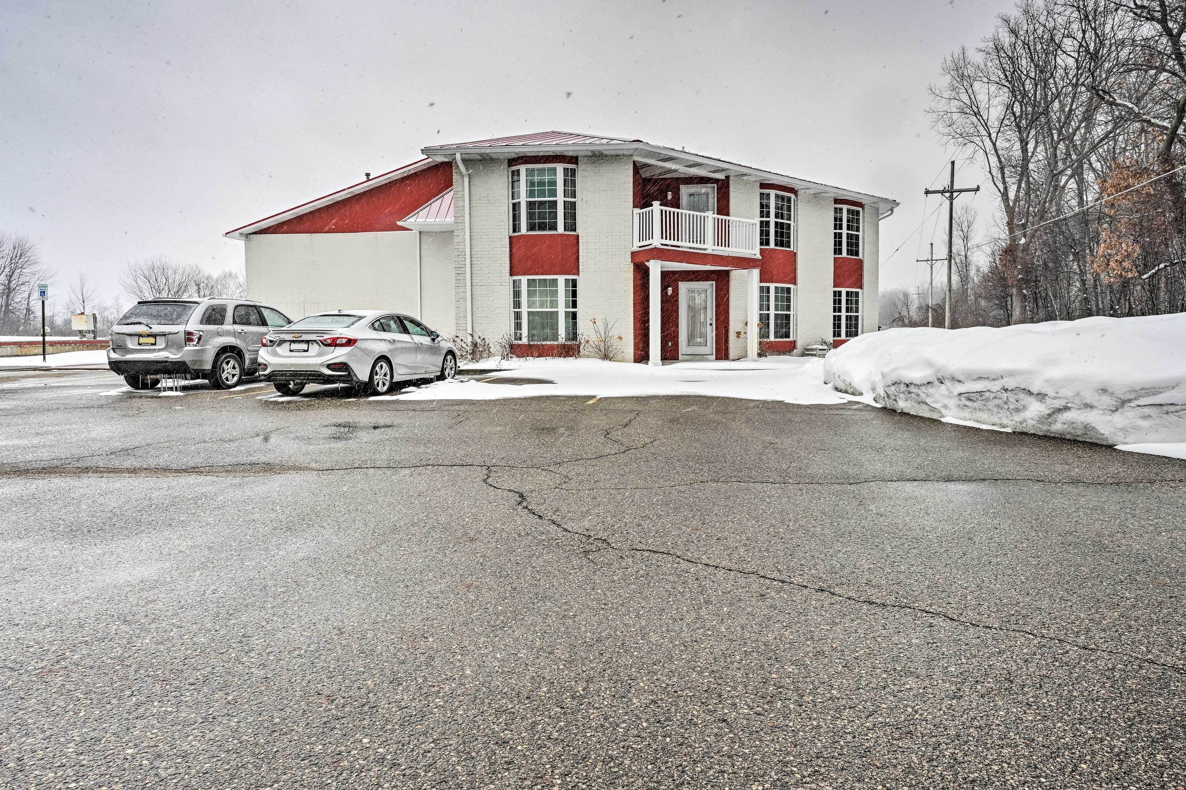 A building with a red and white exterior, a balcony, and two parked cars in front.