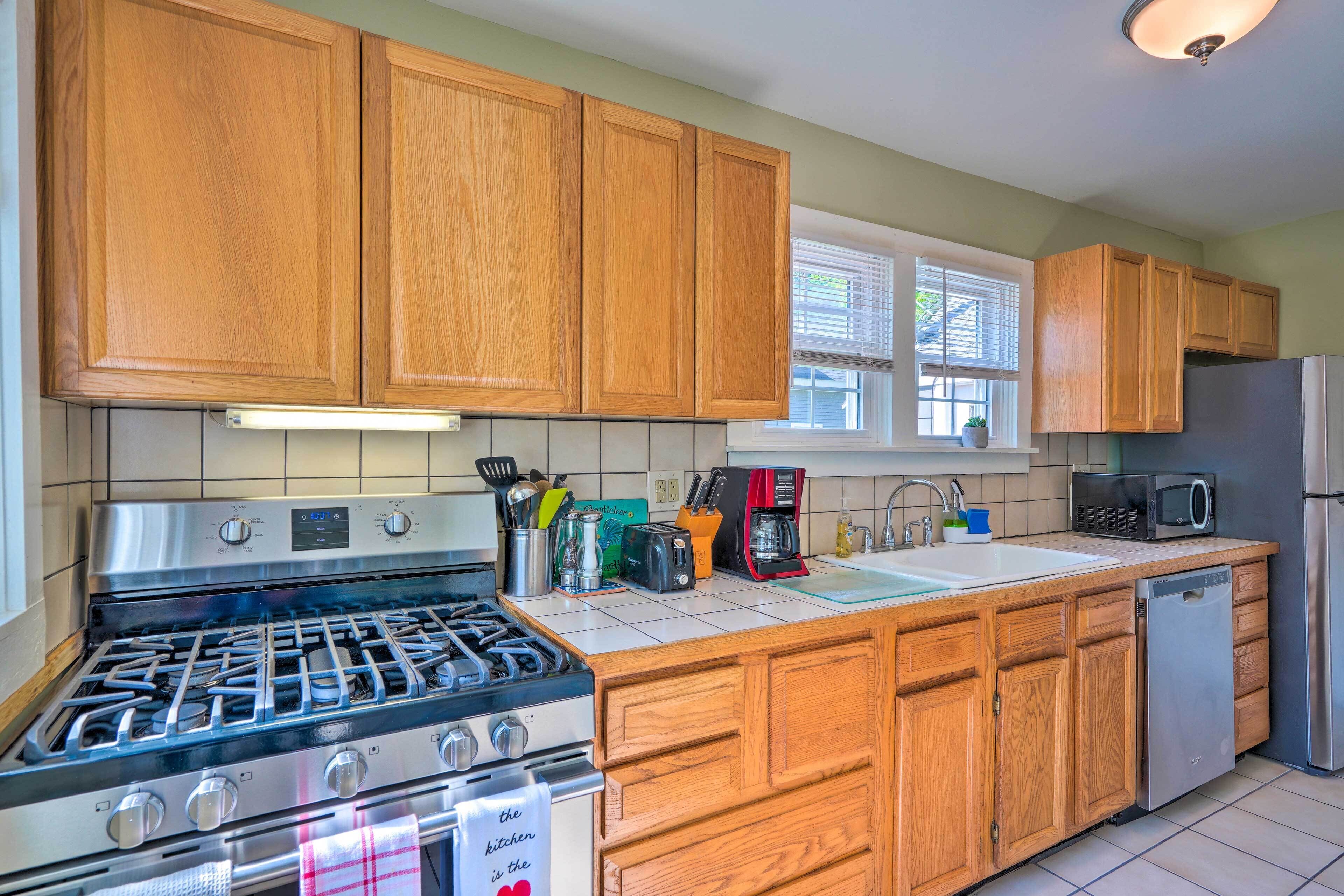 Una cocina con muebles de madera, estufa a gas, cafetera y microondas.