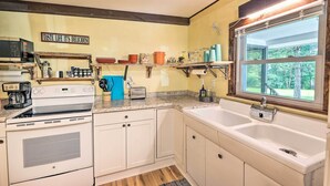 A kitchen with white cabinets, a stove, a sink, and a window overlooking greenery. - Rustic Hideaway w/ Fire Pit < 1 Mi to River! (Hillsboro)