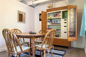 A dining area with a wooden table and chairs, a cabinet with shelves, and a blue striped rug. - Rustic Hideaway w/ Fire Pit < 1 Mi to River! (Hillsboro)