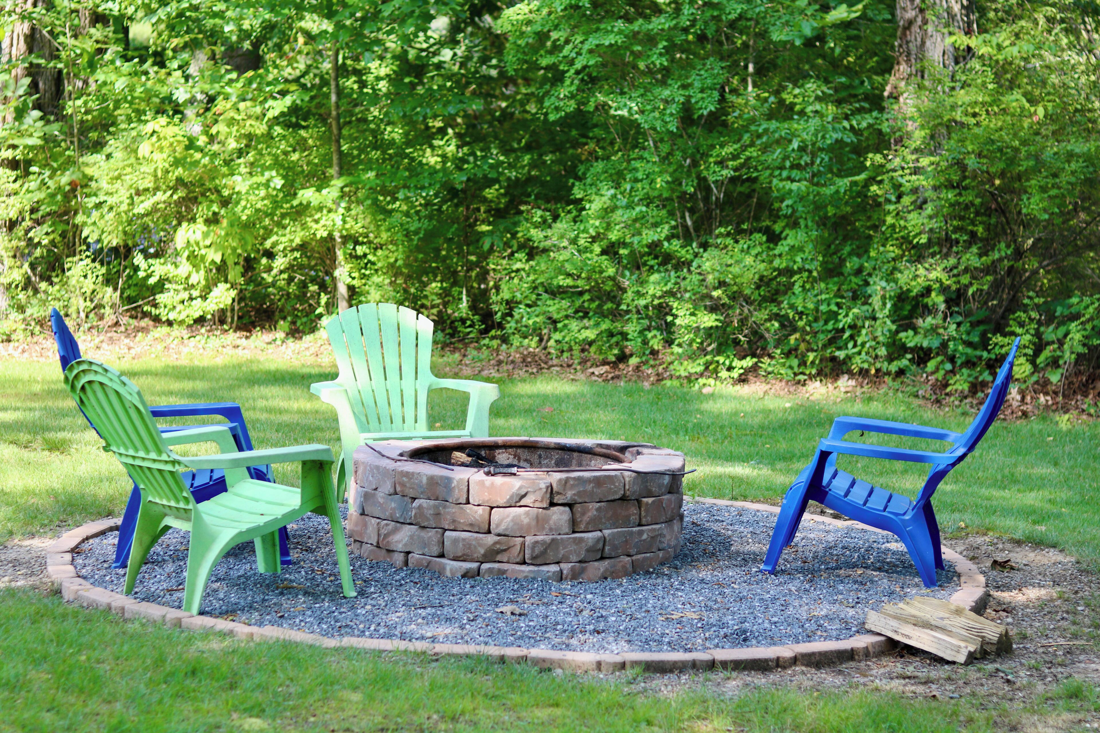 A circular stone fire pit with chairs around it.
