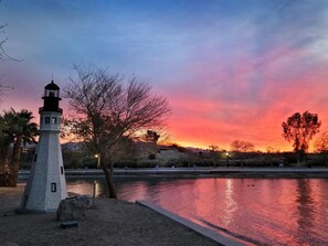 Un phare au bord d’une étendue d’eau calme, au coucher du soleil.