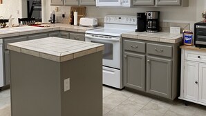 A modern kitchen with grey cabinets, a central island, a microwave, stove, and a coffee maker. - Rocking Horse Retreat, pool, sleeps 10, lake view, minutes to launch & lake (Lake Havasu City)
