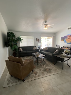 A living room with two sofas, a coffee table, a TV, and a ceiling fan. - Rocking Horse Retreat, pool, sleeps 10, lake view, minutes to launch & lake (Lake Havasu City)