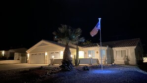 A residential building with a flagpole, a palm tree, and a well-lit entrance. - Rocking Horse Retreat, pool, sleeps 10, lake view, minutes to launch & lake (Lake Havasu City)