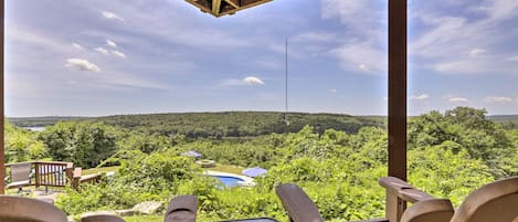 Eine Holzterrasse mit Stühlen mit Blick auf eine üppige Landschaft und ein Gewässer.
