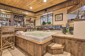 Une pièce spacieuse dotée d’une grande baignoire en bois, de meubles en osier et de divers objets décoratifs.