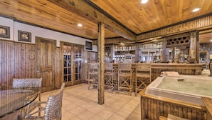 Een houten interieur met een bar, rieten stoelen en een jacuzzi.