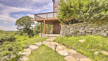 A modern house with a stone wall, wooden deck, and a stone pathway leading to the entrance.