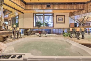 Un grand jacuzzi intérieur avec des poutres en bois et une fenêtre ornée de plantes.