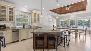 A spacious kitchen with a large island, bar stools, and a view of a lake.