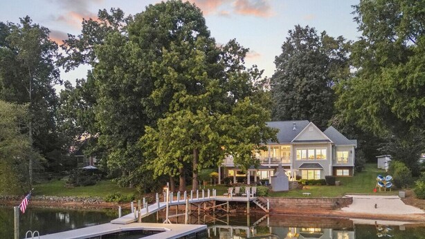 A lakeside property with a dock, a house, and a reflection in the water.