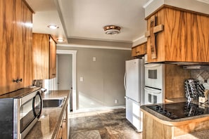 A kitchen with wooden cabinets, stainless steel appliances, and a granite countertop.