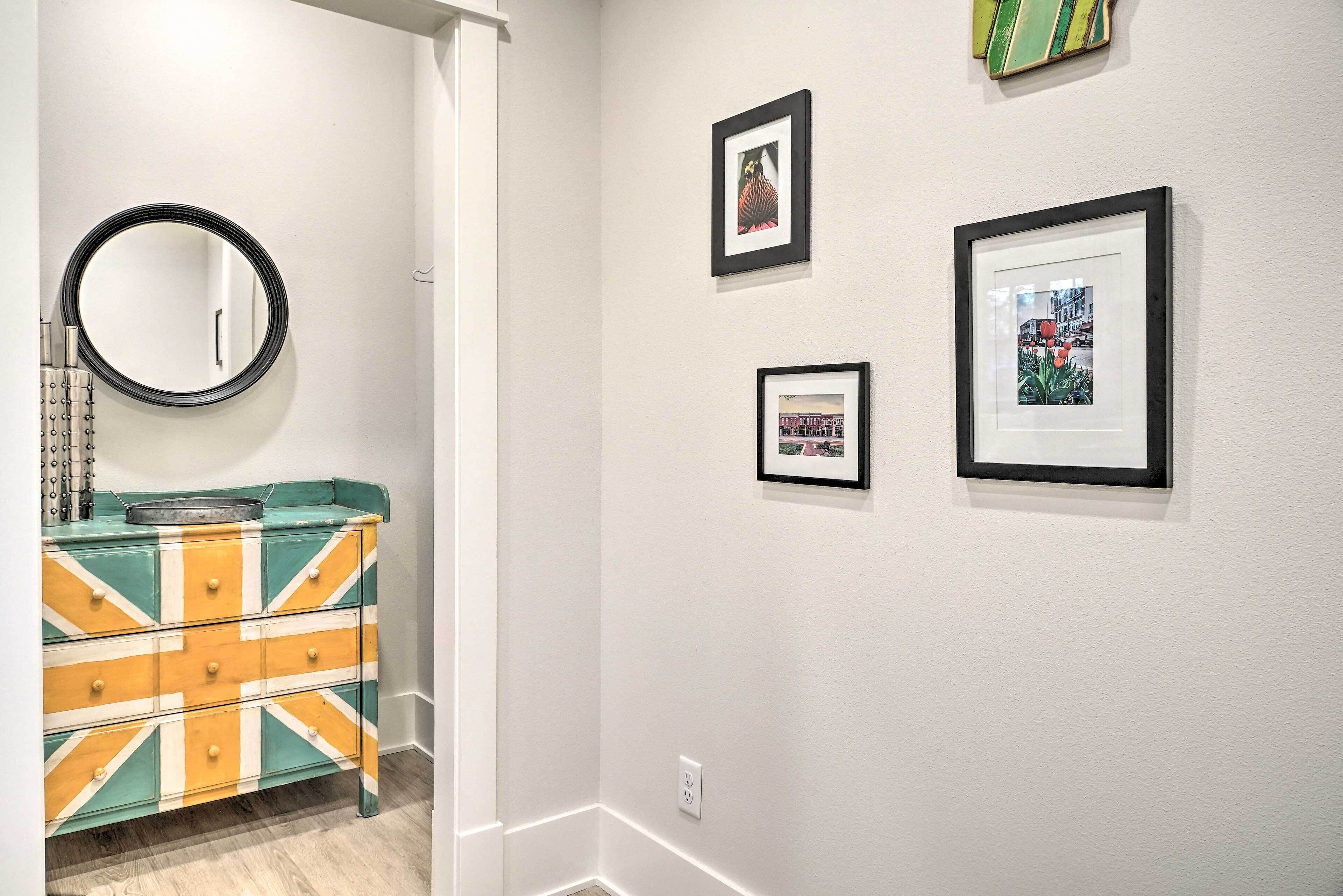 A hallway with a mirror, a dresser with a Union Jack design, and three framed pictures on the wall.