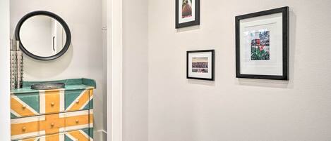 A hallway with a mirror, a dresser with a Union Jack design, and three framed pictures on the wall.