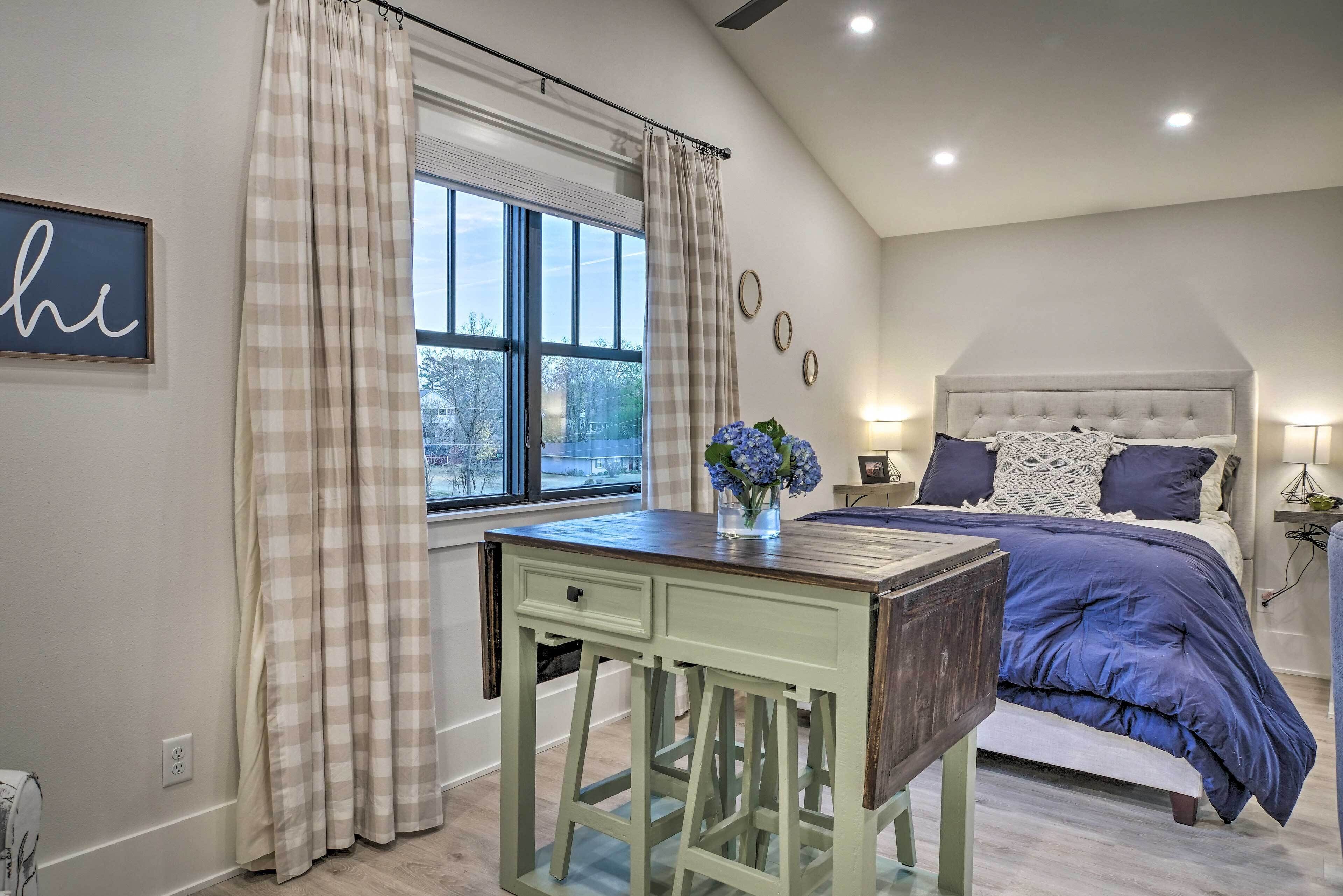 A bedroom with a bed, a desk, and a window with curtains.