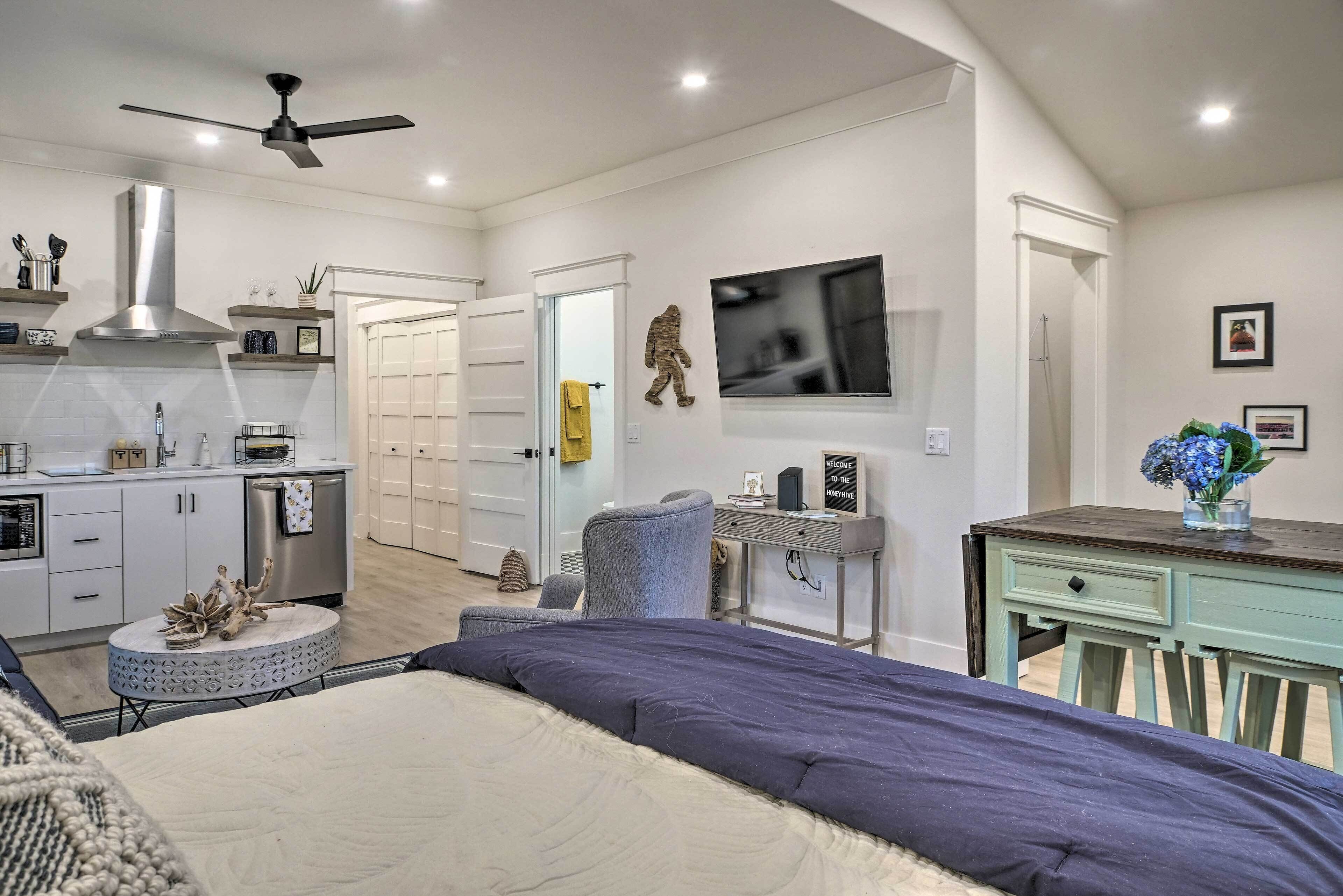 A modern bedroom with a bed, a desk, a chair, and a television.