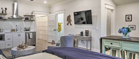 A modern bedroom with a bed, a desk, a chair, and a television.
