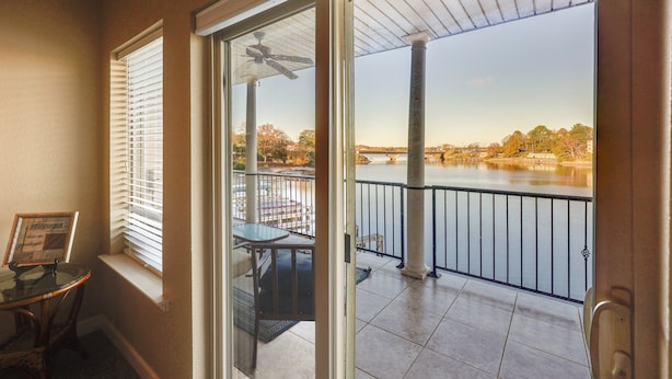 Ein Balkon mit Blick auf einen Fluss und eine Brücke, eine Glastür sowie ein kleiner Tisch mit einem Stuhl.