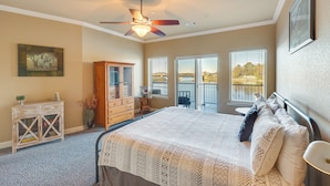 Ein Schlafzimmer mit Bett, Deckenventilator, Kommode, Schrank und Fenster mit Jalousien.
