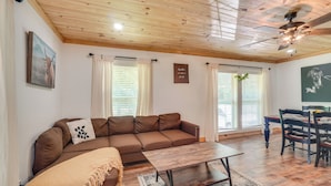 A living room with a brown sofa, a wooden coffee table, and a ceiling fan. - 'creekside Ranch' w/ Porch ~ 2 Mi to Pkwy (Pigeon Forge)