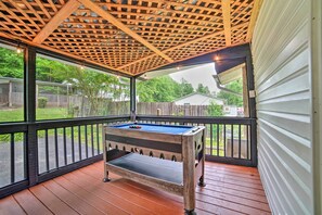 Un espace extérieur abrité comprenant une table de billard, une terrasse en bois et une vue sur le jardin.