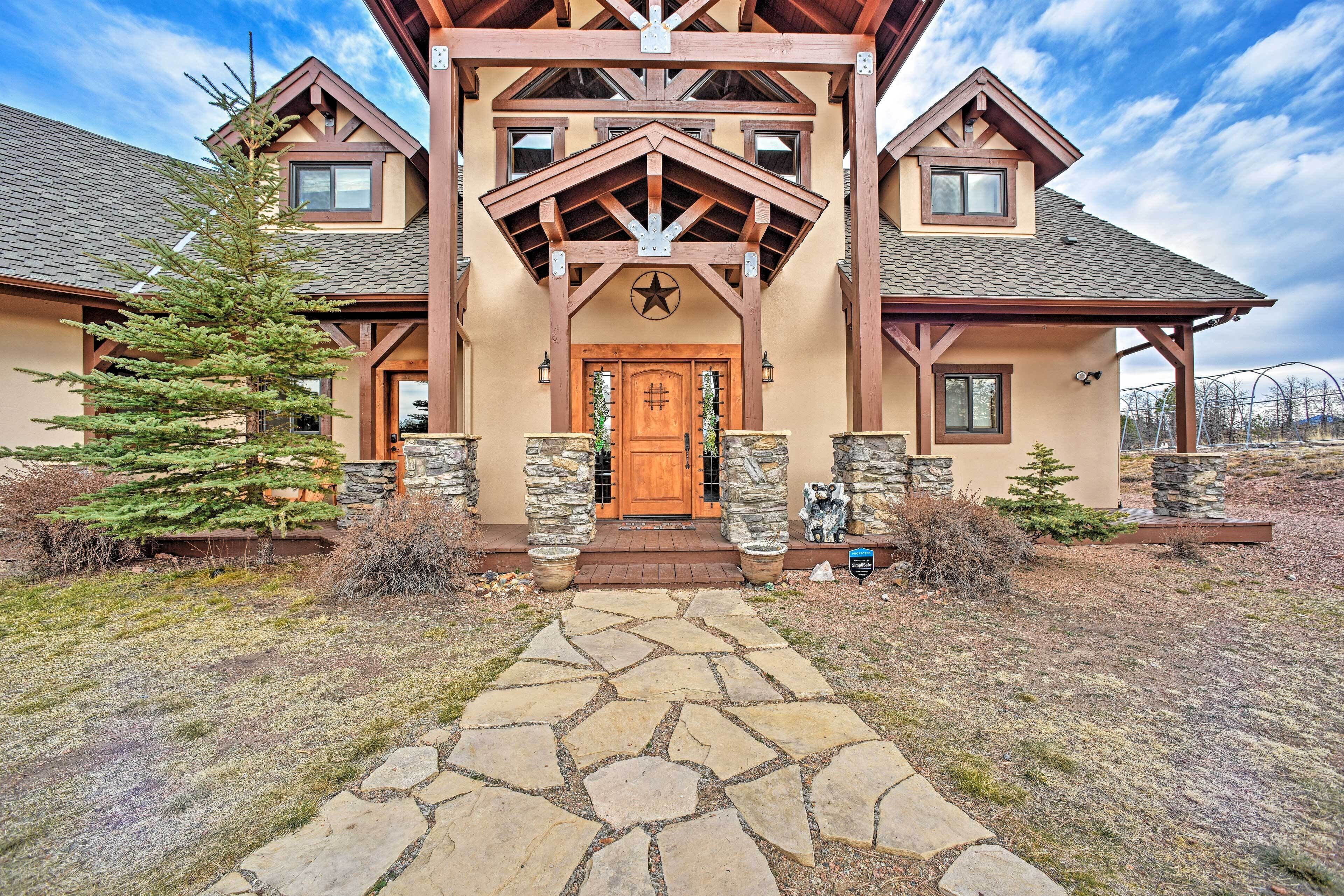 A large, two-story house with a stone facade, a prominent wooden entrance, and a stone pathway leading to the door.