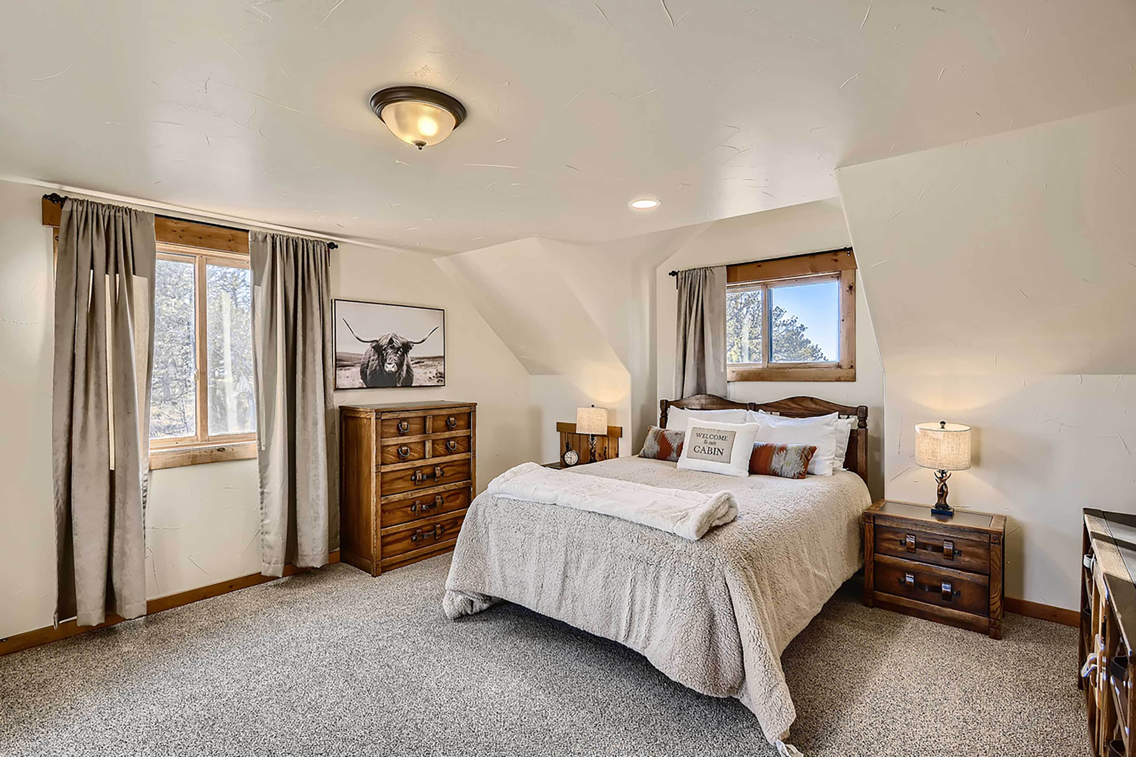 A bedroom with a large bed, wooden dresser, and a nightstand with a lamp.