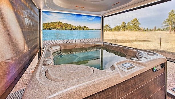 Un jacuzzi con vista a un lago y una terraza de madera.