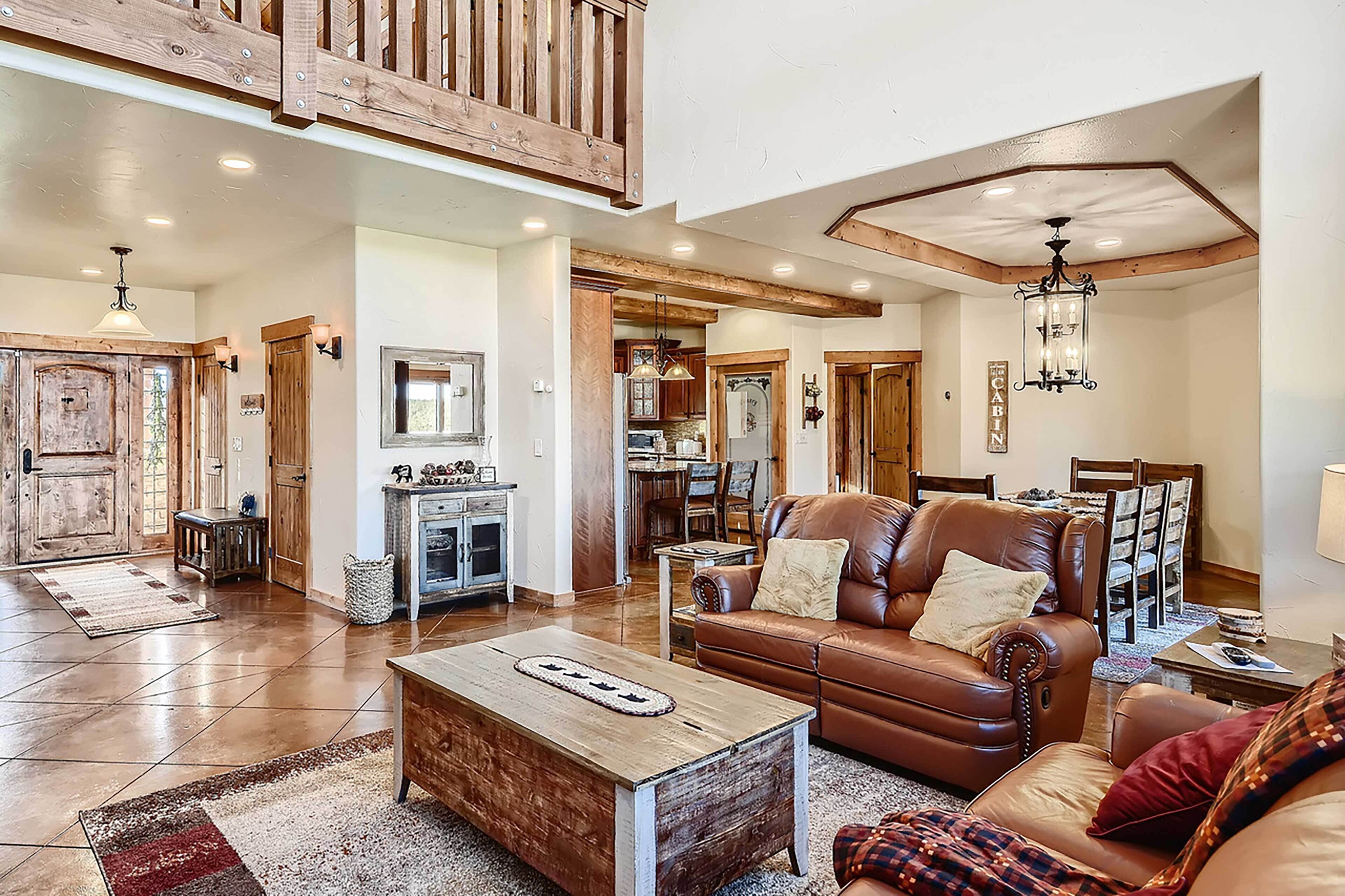 A spacious living area with a wooden coffee table, leather sofa, and a dining area with wooden chairs.
