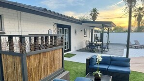 A patio area with a white brick wall, a bamboo fence, and outdoor furniture including a sofa and chairs. - UPDATED Shasta FUN, Pool & Putting Green, sleeps 11 (Lake Havasu City)