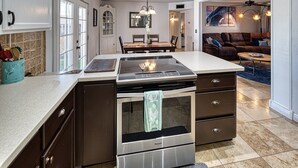 A modern kitchen with a built-in stove, oven, and dishwasher, a dining area with a table and chairs, and a living room with a sofa and coffee table. - UPDATED Shasta FUN, Pool & Putting Green, sleeps 11 (Lake Havasu City)