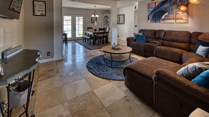 A spacious living room with a brown leather sofa, a coffee table, and a dining area in the background. - UPDATED Shasta FUN, Pool & Putting Green, sleeps 11 (Lake Havasu City)