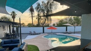 A pool area with lounge chairs, a red umbrella, and a bar counter. - UPDATED Shasta FUN, Pool & Putting Green, sleeps 11 (Lake Havasu City)