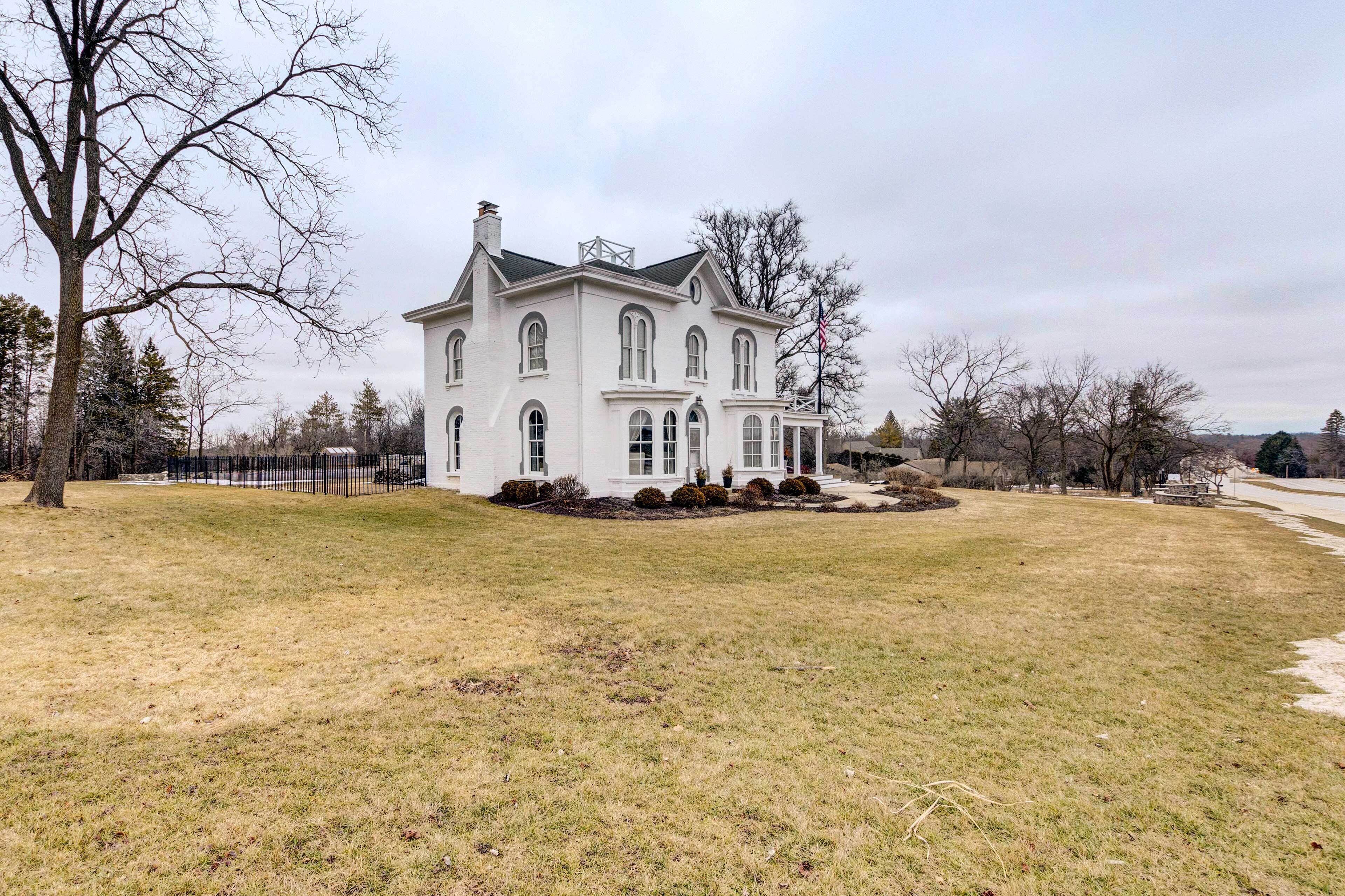A large, white, two-story house with a symmetrical facade, multiple windows, and a front porch.